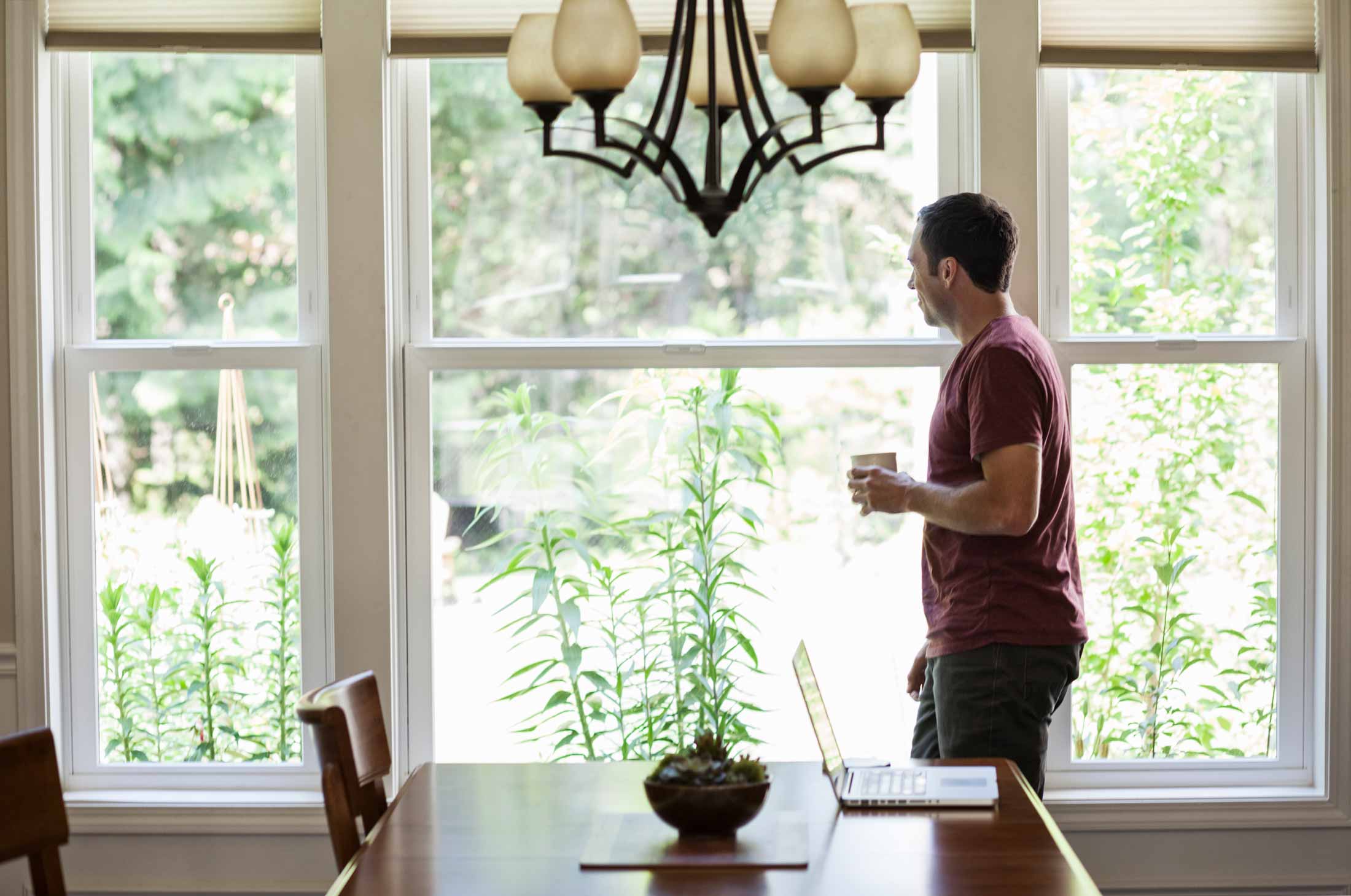 man drinking coffee next to large window
